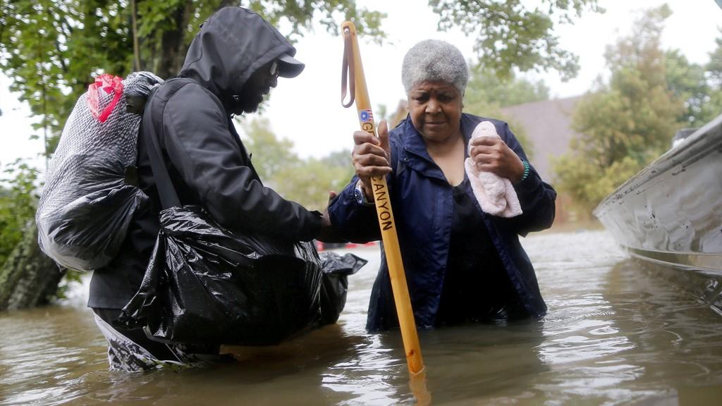 Andrew Mitchell helps his neighbor Beverly Johnson onto a rescue boat to escape the rising flood waters from Tropical Storm Harvey in Beaumont Place, Houston, Texas, U.S., on August 28, 2017.