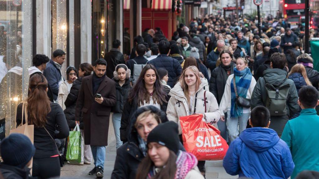 Crowds of winter shoppers on a busy High Street during the Boxing Day sales December 2024