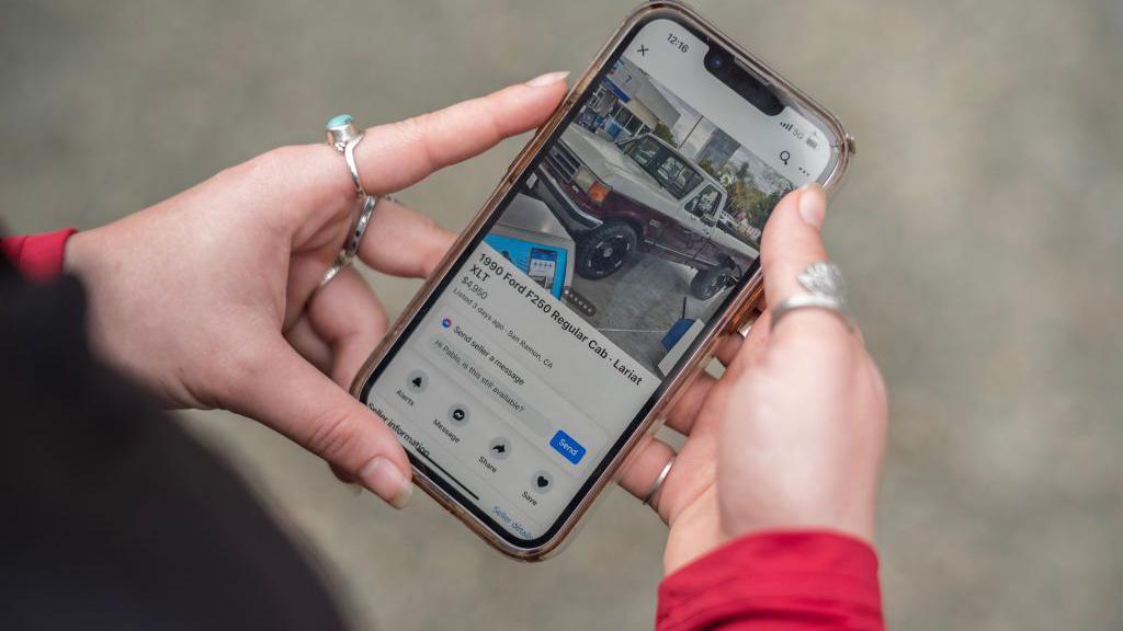 Person holds phone with Facebook Marketplace open, showing a car.