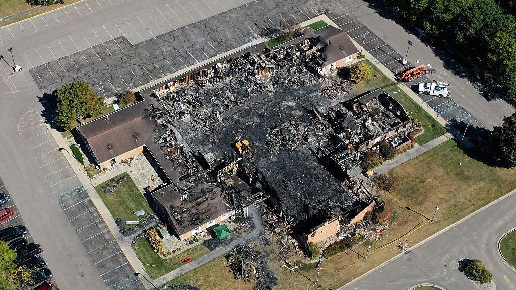 In this aerial view, the burned remains of the Church of Jesus Christ of Latter-day Saints Michigan, on October 1, 2025 in Grand Blanc, Michigan. The building's middle is entirely hollow, charred and filled with debris and ash. 