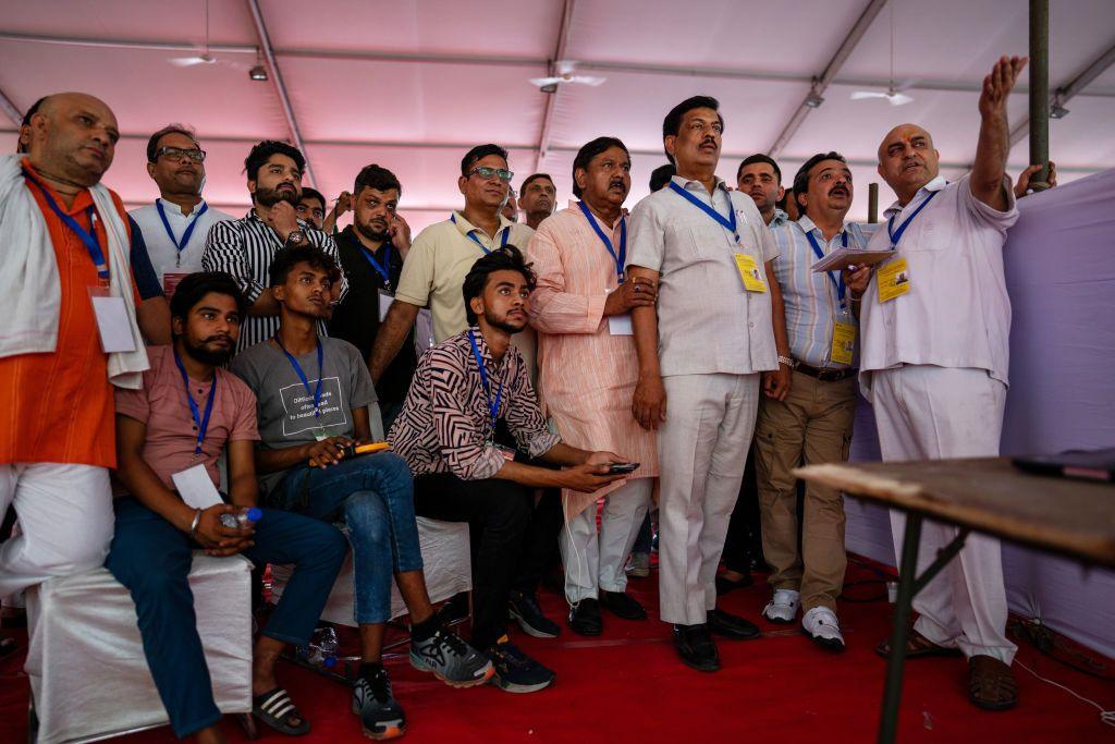 Various party officials with stern expressions monitor live results at a vote-counting center for the national elections in New Delhi,