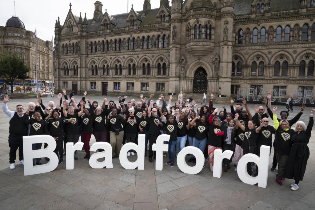 A large group of people standing behind giant white letters spelling out Bradford