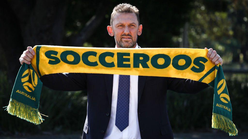 Tony Popovic holding an Australia scarf above his head