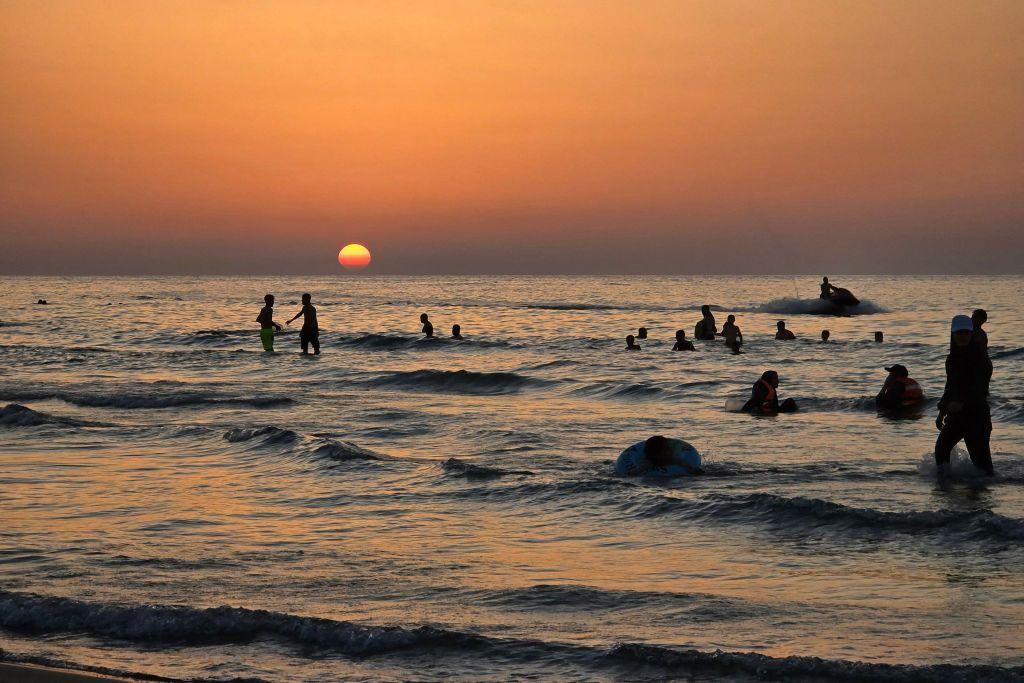 People swim in the sea at sunset in Qarabuli, Libya - Saturday 20 July 2024