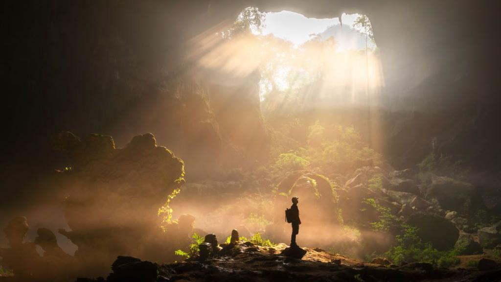 A man poses for a photo under the Nongxiang Sinkhole 