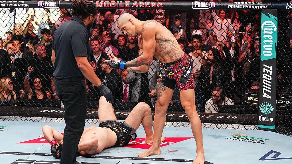 Alex Pereira stands over Magomed Ankalaev after winning their fight