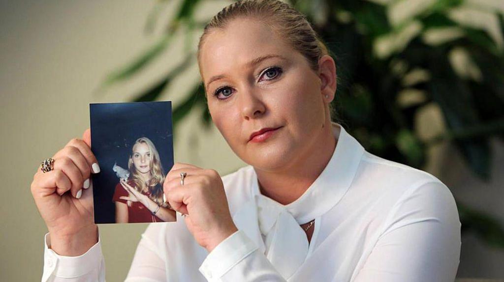 Virginia Giuffre, dressed in white, holds a photo of herself as a teen, when she says she was abused by Jeffrey Epstein, Ghislaine Maxwell and the former Prince Andrew, among others.