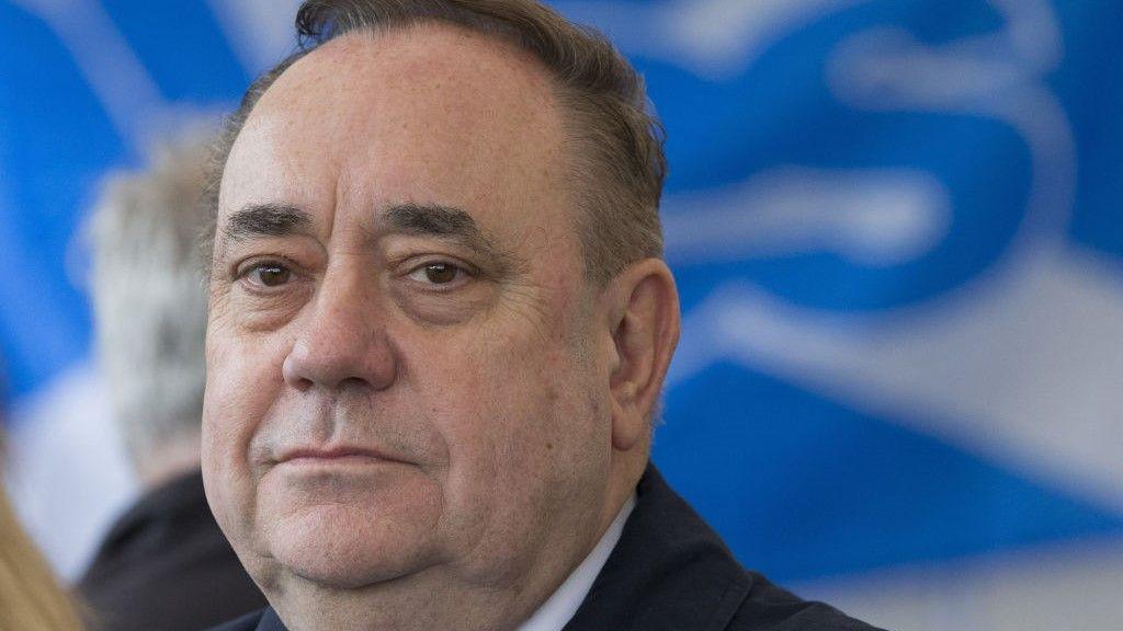 Alex Salmond in extreme close-up looking towards the camera. There is a 'Yes' flag behind him.