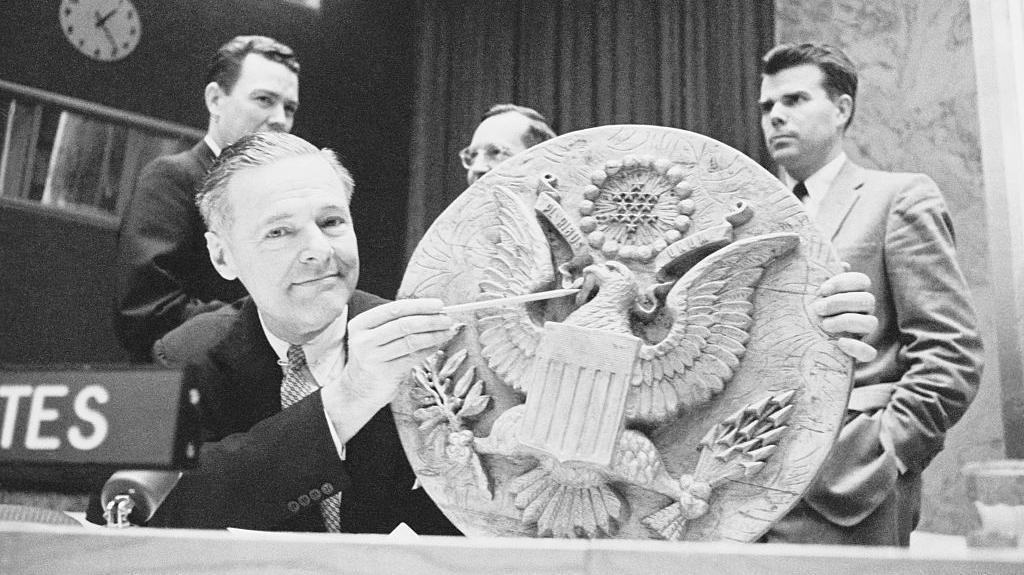 United States Representative to the United Nations, Henry Cabot Lodge, points to the spot on the seal where it has been bugged, the image is black and white.