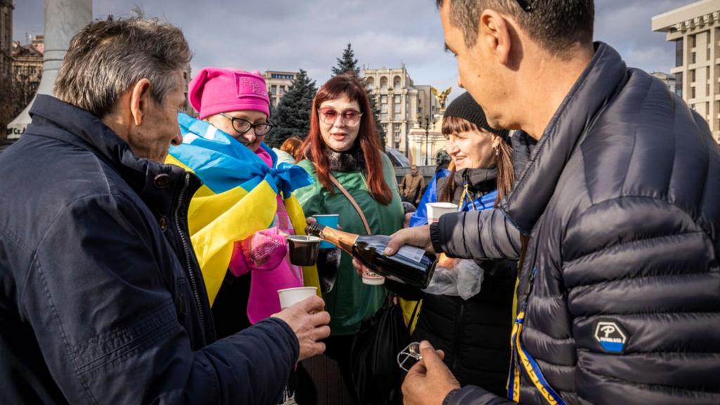 People drink sparkling wine, waves flags and sing songs as they celebrate the liberation of part of the city of Kherson in Maidan Square