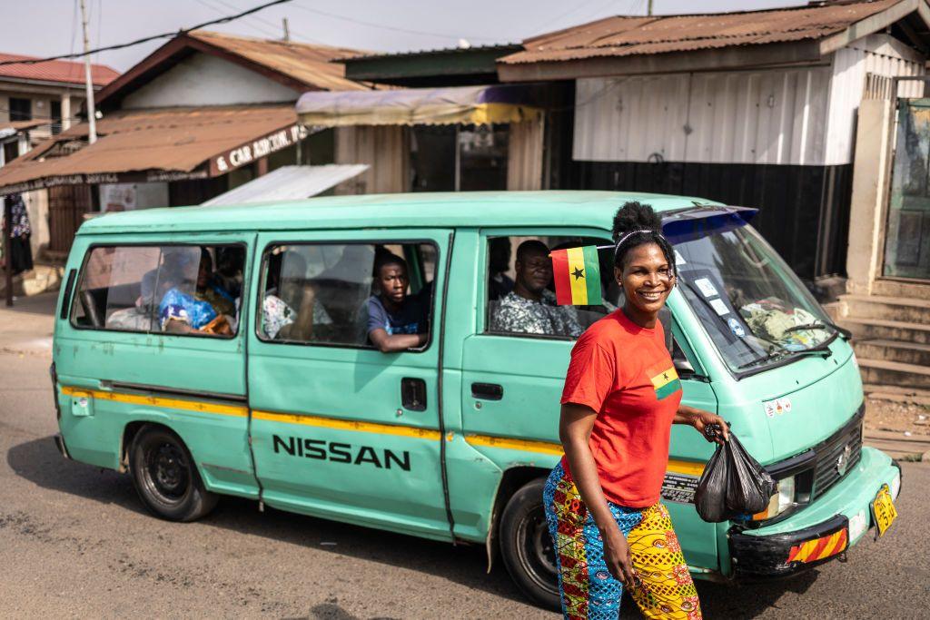 A woman walking past a bus wears the country's national flag on her her and her T-Shirt.