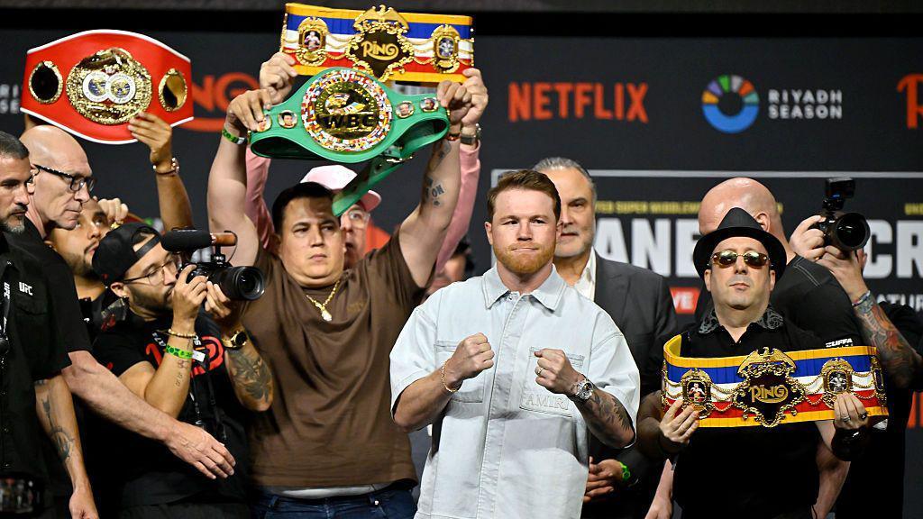 Saul 'Canelo' Alvarez stands pinch his fists up pinch his world titles astir him