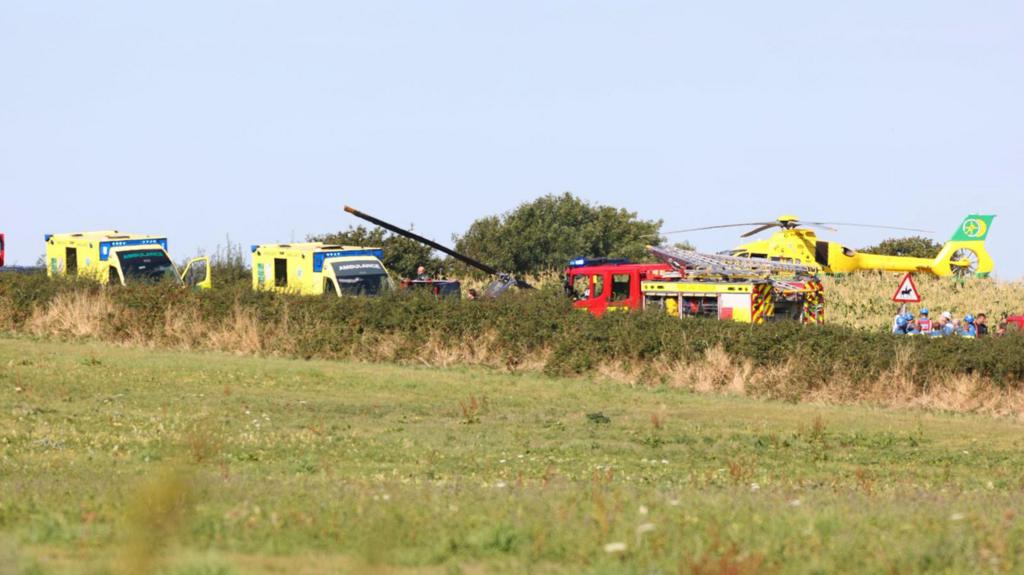 Emergency service vehicles in a field at site of helicopter crash.