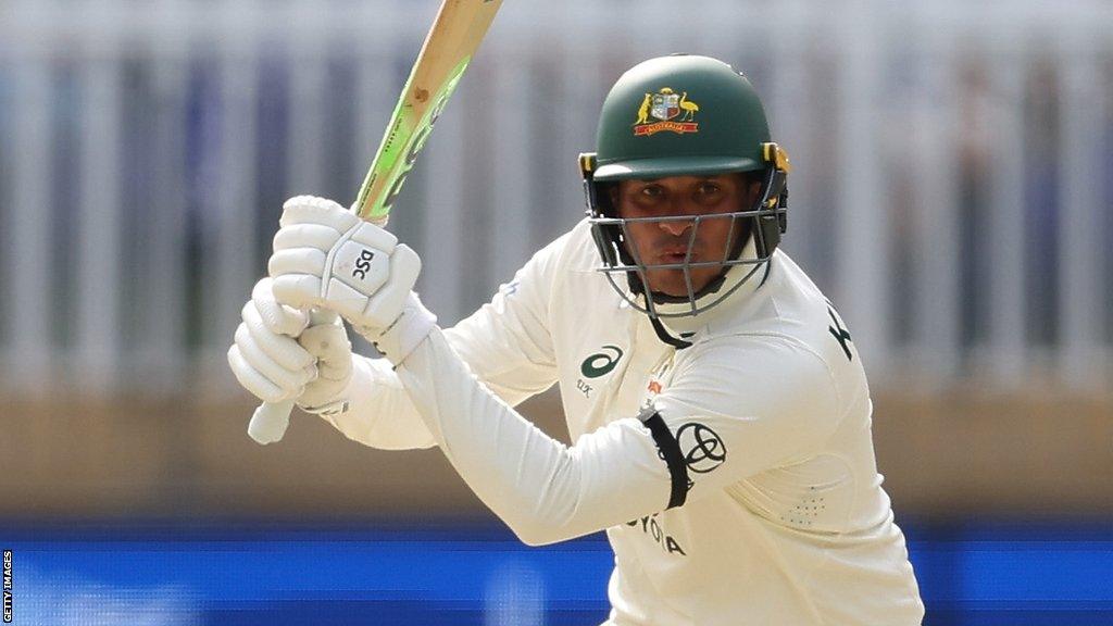 Australia batter Usman Khawaja, wearing a black armband, plays a shot