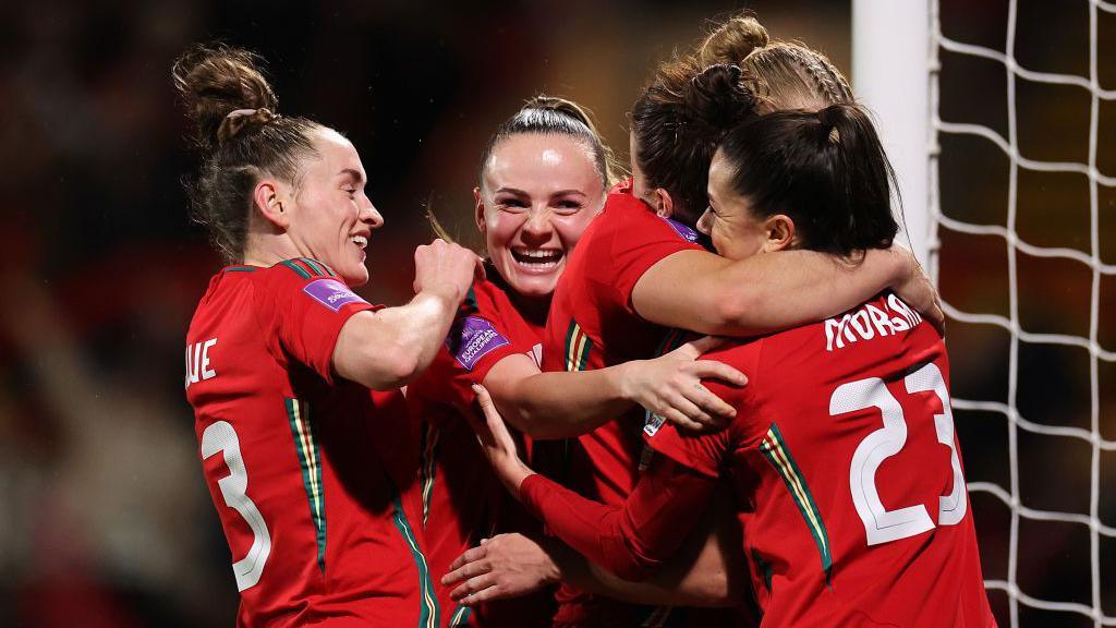 Angharad James of Wales (hidden) celebrates scoring her team's fourth goal with teammates during the UEFA EURO 2025 Women's Qualifiers.