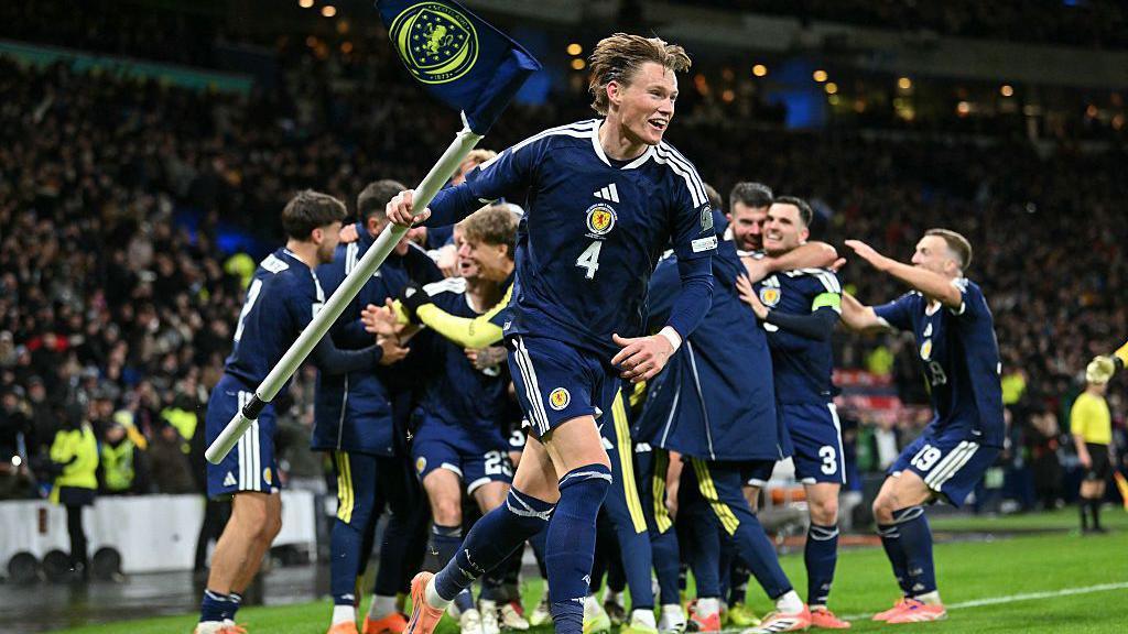 Scotland's midfielder Scott McTominay grabs the corner flag in celebration