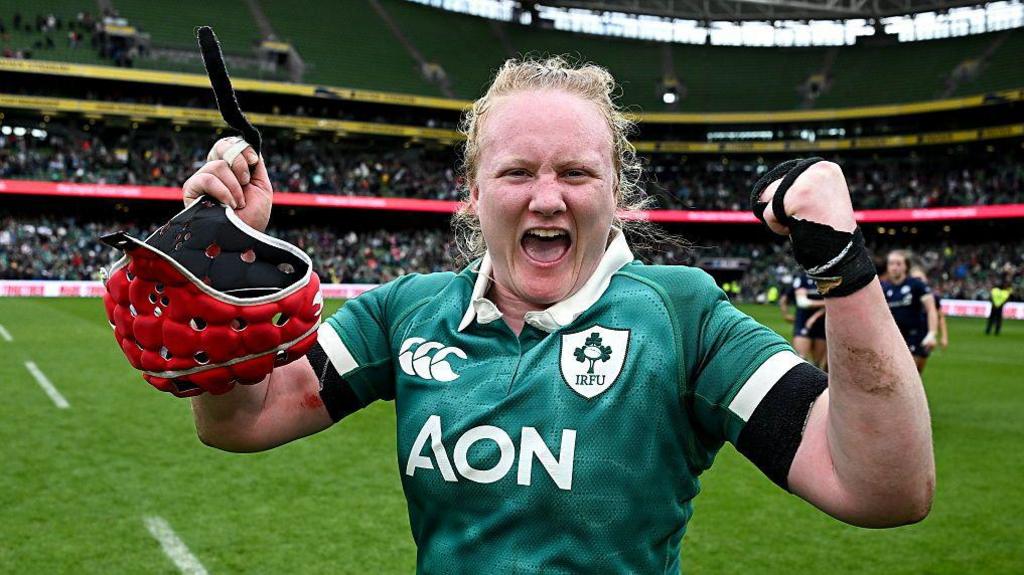 Aoife Wafer holding her red helmet looking at the camera and cheering