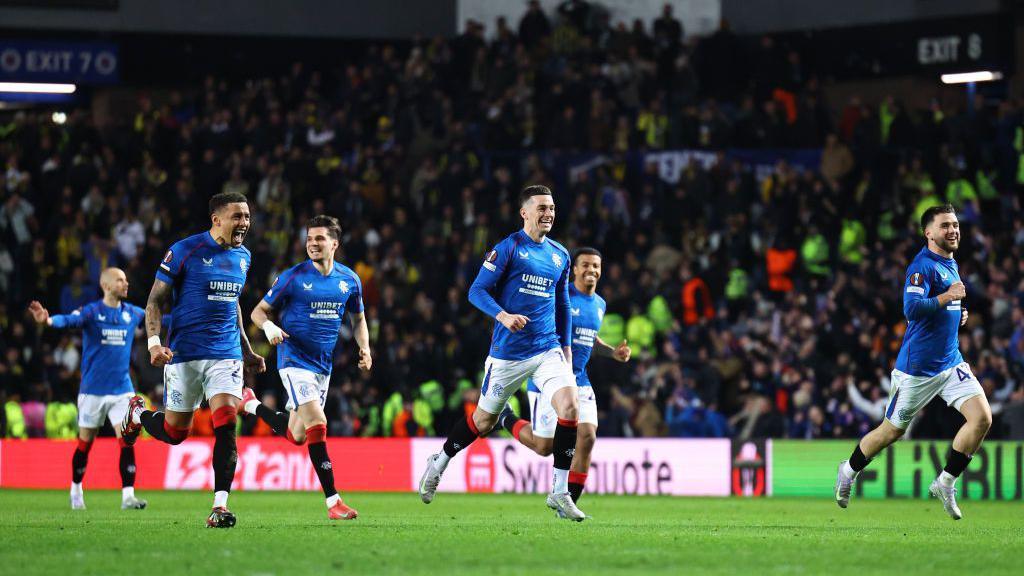 Smiling Rangers players running to the side of the pitch after winning their penalty shoot out against Fenerbahce. 