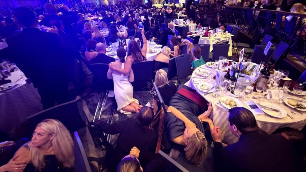 Attendees duck under tables after shots fired at the White House Correspondents' Dinner