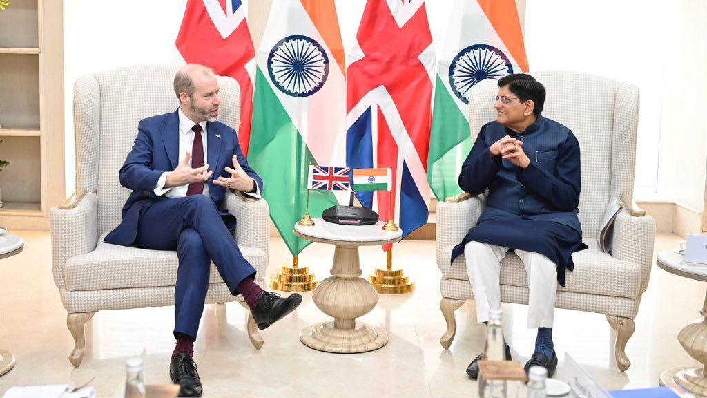 Indian commerce minister Piyush Goyal, wearing a blue shirt and jacket with white pants, holding talks with UK Business Secretary Jonathan Reynolds, wearing a blue suit with white shirt and maroon tie, in Delhi. 