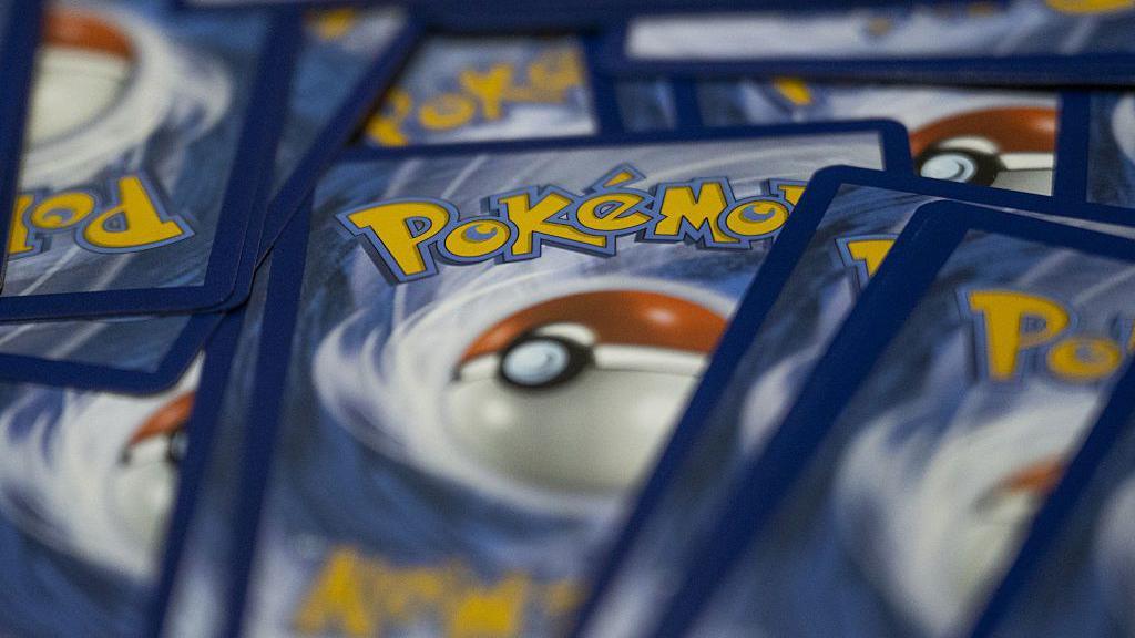 A pile of pokemon cards, with the pokemon logo and pokeball displayed on the back of cards. 