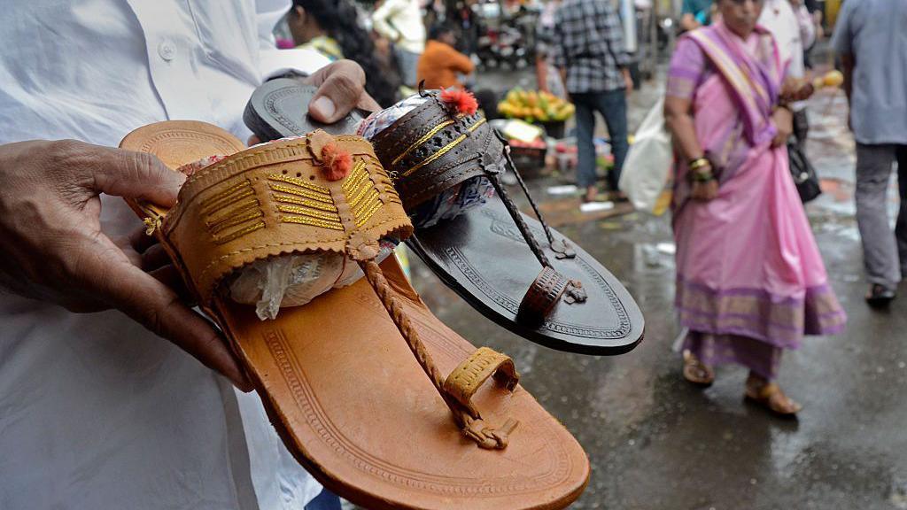 A shopkeeper holds Kolhapuri sandals, an Indian traditional footwear, at a roadside shop in Mumbai, India, on July 4, 2025. T
