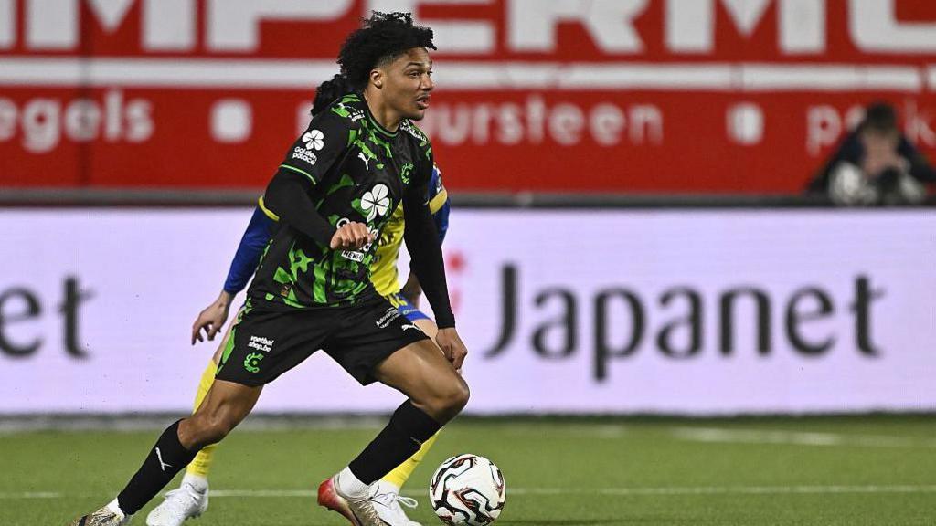 Oluwaseun Adewumi in action for Cercle Bruges wearing a black and green playing shirt, black shorts and black socks