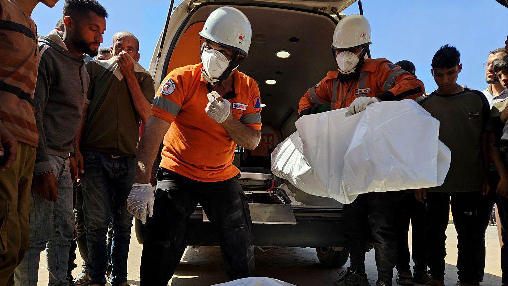 Civil defense teams carry the body of a Palestinian following an Israeli airstrike on residential areas in central Khan Yunis, southern Gaza, on May 23, 2025.