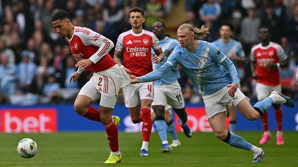 Erling Haaland and William Saliba wrestling for the ball during the League Cup final in March 2026.