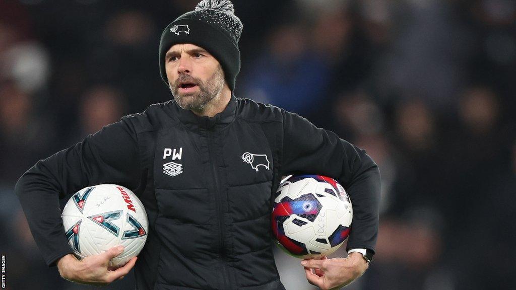 Derby boss Paul Warne holding some football's as his team warms us