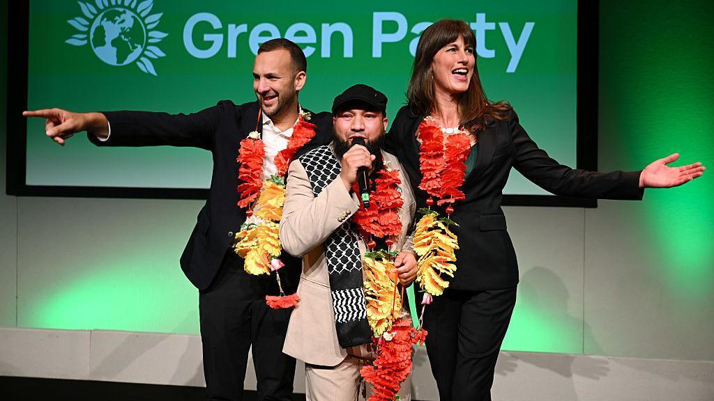 Green Party leader Zack Polanski (l), Mothin Ali, Deputy Leader of the Green Party and Rachel Millward, Deputy Leader of the Green Party react to the crowd after both of the deputy leader speeches on the second day of the Green Party Conference 