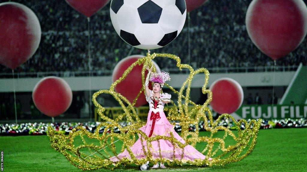 A performer dances beneath a balloon designed in the pattern of a soccer ball during the opening ceremony on November 16, 1991, in Guangzhou