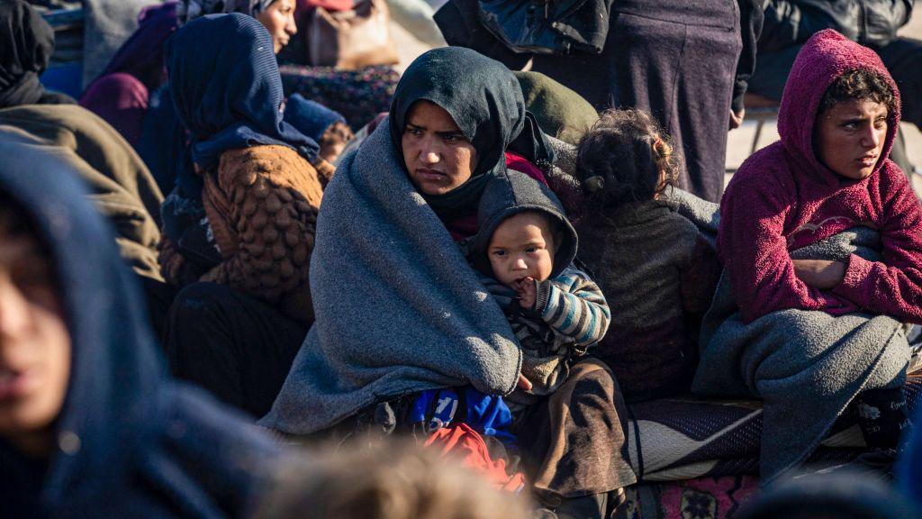 A Syrian Kurdish woman holds a child in Tabqa after fleeing from north of Aleppo (4 December 2024)