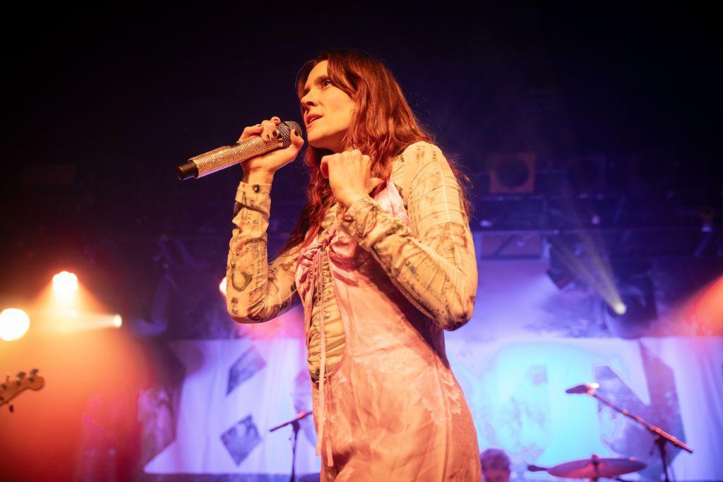 Kate Nash wears a vintage dress and sings into a microphone on stage in Leeds
