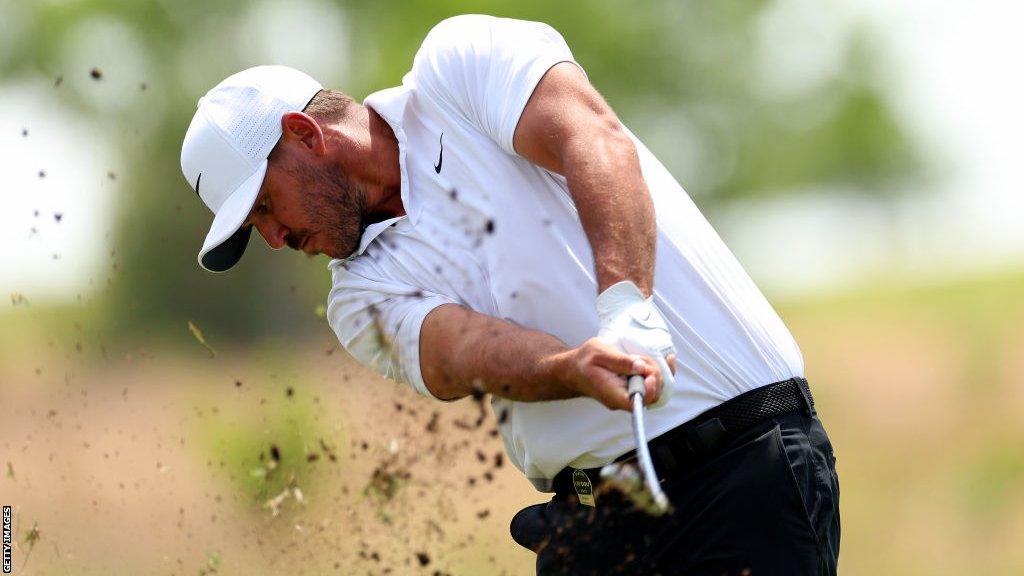 Brooks Koepka hitting a ball out of a bunker