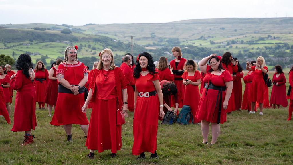 A group of people who are dressed in red dresses and ready to dance on the moors in Yorkshire. 
