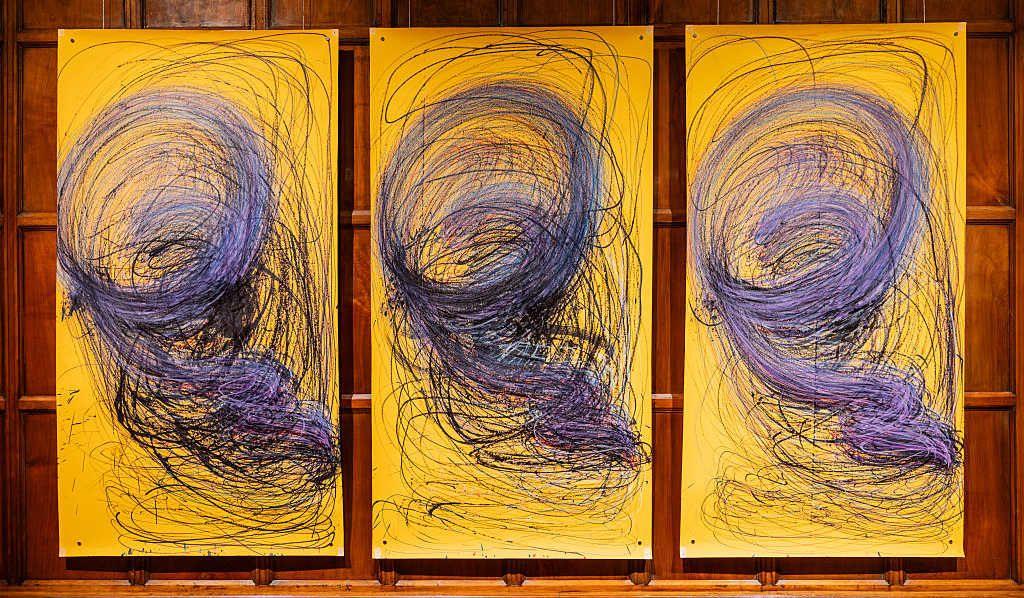 Three large yellow paintings by Nnena Kaluin a row with identical blue swirly patterns 