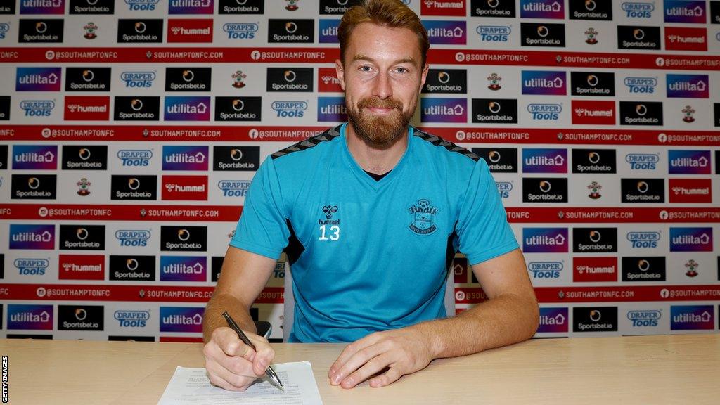 Joe Lumley poses signing a piece of paper at his unveiling by Southampton