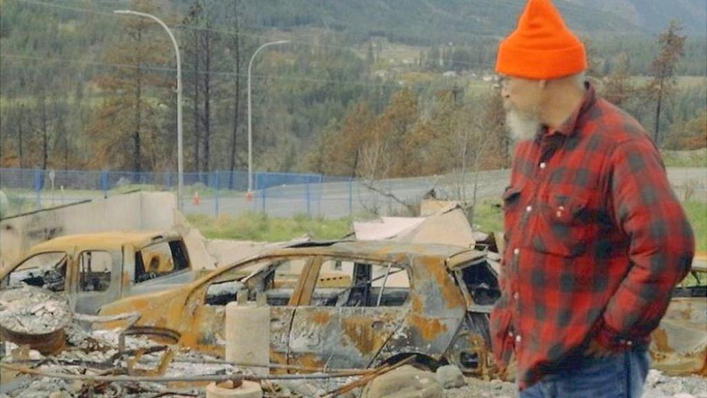 Man looking at burnt-out cars