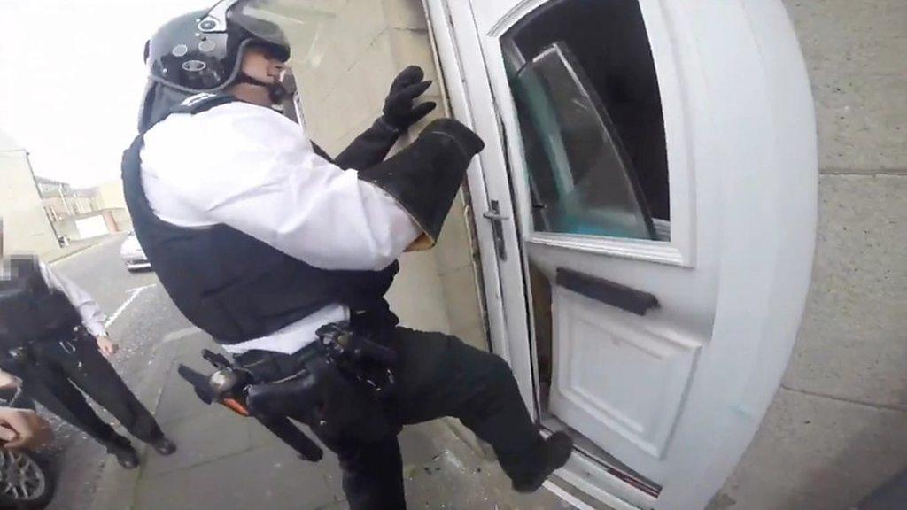 A police officer kicks in a door of a house