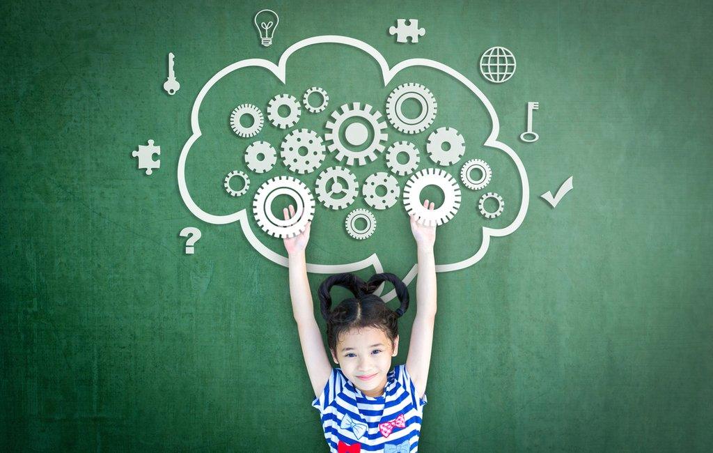 A girl strands beneath the cartoon image of a brain full of cogs