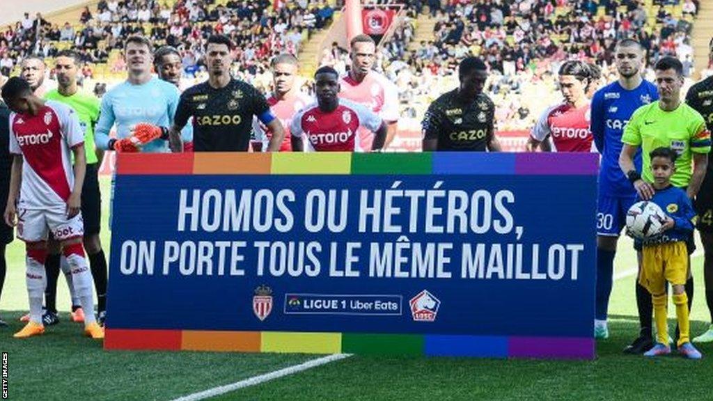 Monaco and Lille players hold a banner that reads "gay or straight, we all wear the same jersey" before their game on 14 May 2023