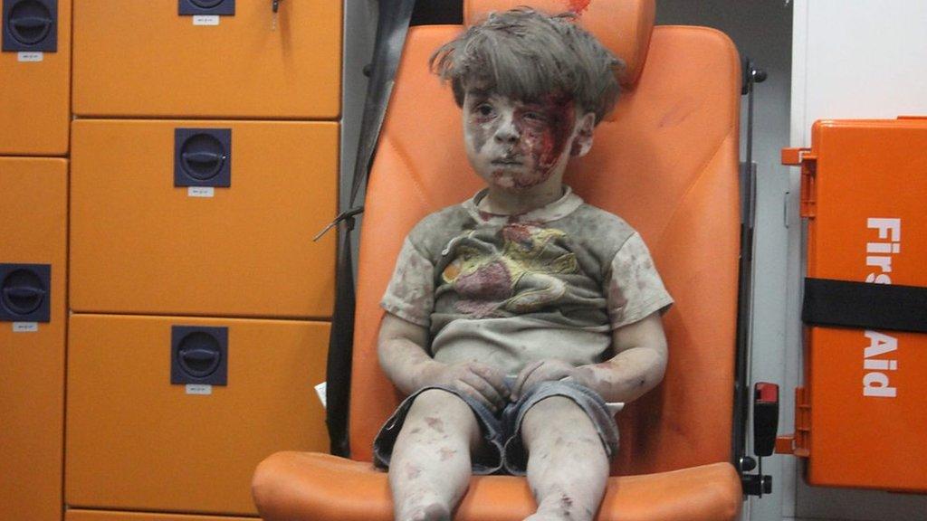 A boy sits in shock after an explosion