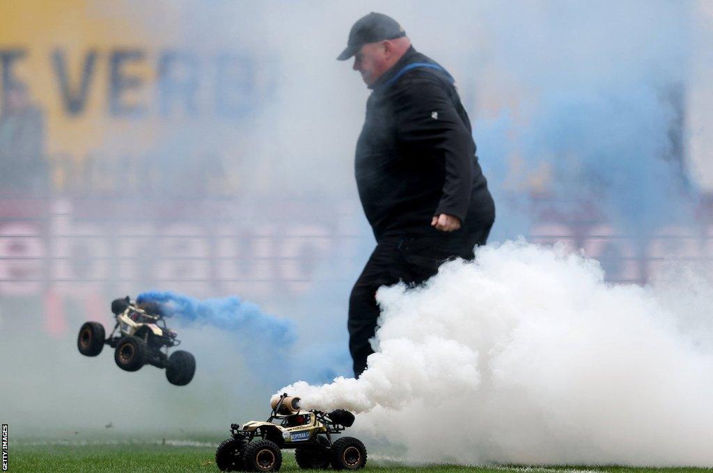 A steward kicking one of the cars off the pitch