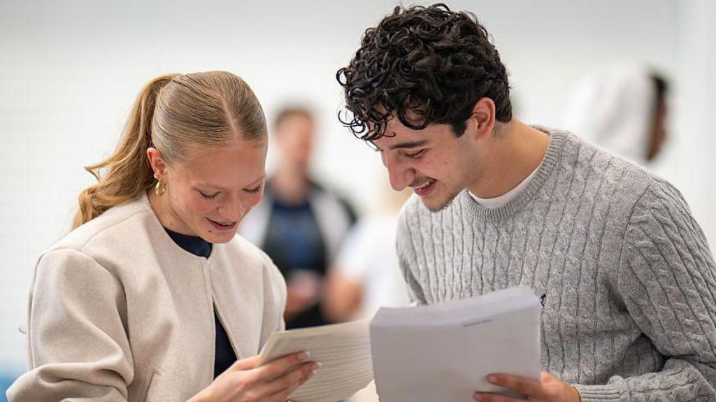 A girl and a boy open their results and look at their sheets of paper.