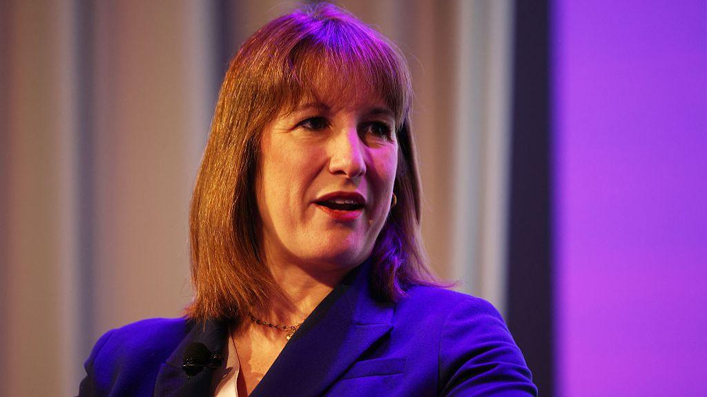 Rachel Reeves, a woman in her 40s with medium-length brown hair, is wearing a blue suit.