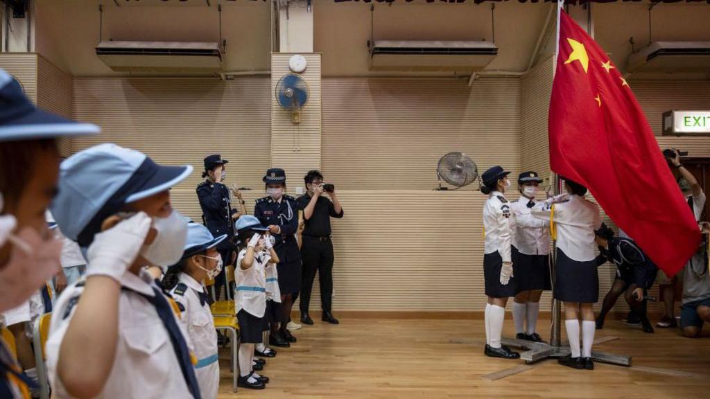 Students salute while watching the flag-raising ceremony to commemorate the 72nd anniversary of the establishment of the People's Republic of China at a school in Hong Kong