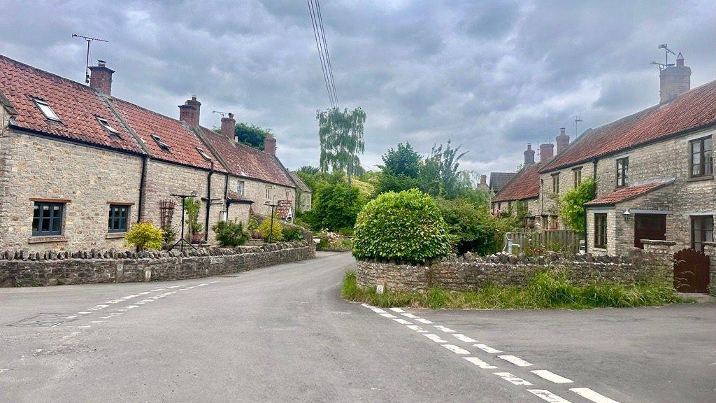 Small winding countryside lane lined either side with cobbled brick houses and terracotta slate roofs