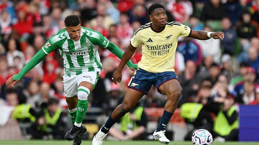 Myles Lewis-Skelly of Arsenal is put under pressure by Nelson Deossa of Real Betis