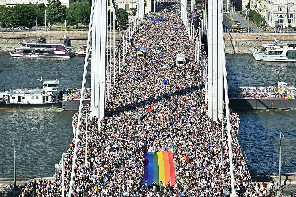 Vast crowd of people on Budapest's Elisabeth Bridge, including big rainbow flag